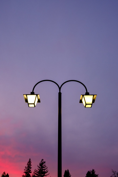 Street lamps with pinkish clouds glowing post-sunset