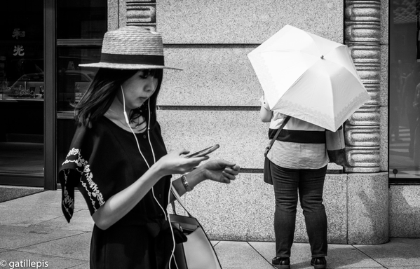 Dona amb barret de palla, mentre mira el mòbil.