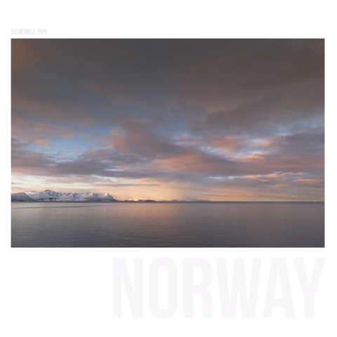 Soft clouds over a calm ocean, with a retreating sun painting pink and yellow hues across the sky.