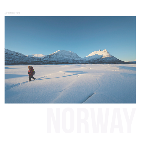 Frozen lake with fractured ice cap. A photographer walks away from the centre of the scene, with the impressive peaks of Nova behind her.