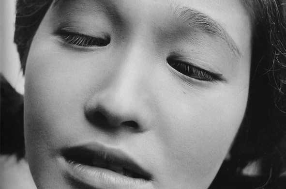 le visage d’une jeune femme aux yeux bridés mi-clos