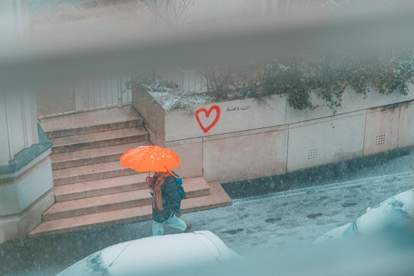 This is a photo I actually took out of my window on a snowy day. It points to the street where a oerson with a bright orange umbrella is walking, leaving traces in teh snow. Behind them is a wall with a simple graffiti: a red heart and the words "alles gut" which literally says "all good" but I would translate it more as "everything's ok" or something like that. I think I've posted this before but I actually enjoy it every time I come across it. 