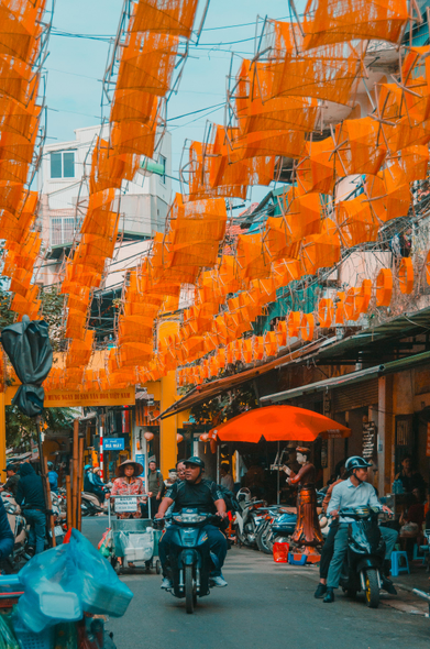 I took this photo a lifetime ago, I believe in Hanoi, Vietnam. It shows a busy street, with people on bikes and street vendors and there was this orange decoration hanging above the street and I'm sorry, I'm afraid I can't describe it any better than that. The image to me displays a lively colourful scene in what at the end of the day may just be a street. I have so little recollection of many parts of this trip but this image struck me. 