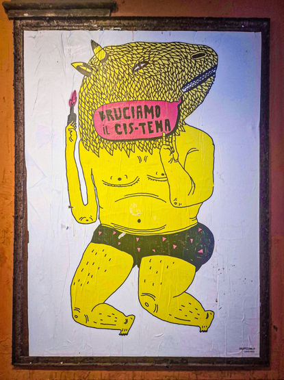 A vibrant, digital drawing in a cartoon style features a yellow anthropomorphic animal with a warthog (?) head, holding a pink lipstick in its right hand. The animal wears black boxer shorts and has a pink sign under its head reading "BRUCIAMO IL CIS-TEMA."  "LET'S BURN THE CIS-TEM" .The background is a textured white with a brown wooden frame.
