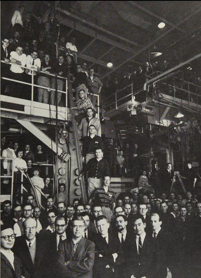 a black and white photo of a large number of white men in suits at a scientific facility