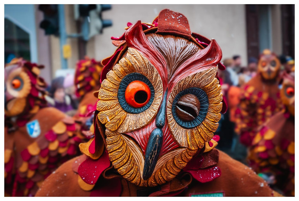 Mensch in hölzerner Maske, die eine Eule darstellt.