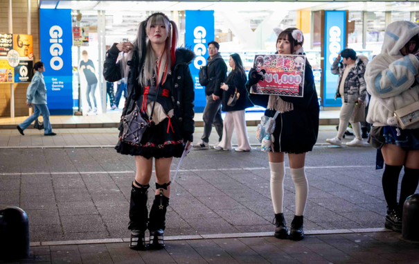 Noies dretes al carrer fent de reclam per captar clients per als bars anomenats Gyaru's bars.