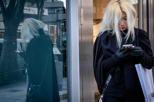 Noia rossa i el seu reflex en un aparador d'Omotesando a Tòquio.