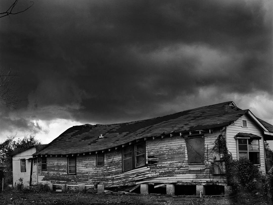 après l’ouragan et les inondations, une maison de planches affaissée sous un ciel menaçant