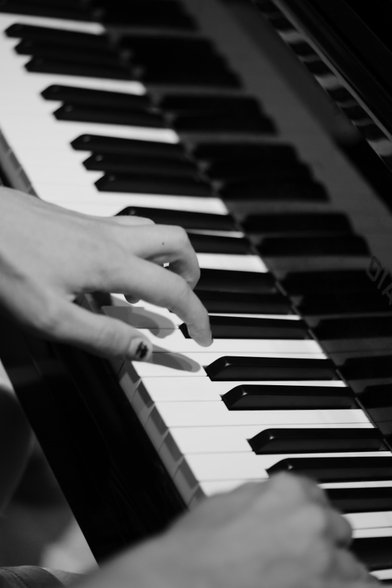 black and white photo of a man playing a piano, close-up of his hands on the keys