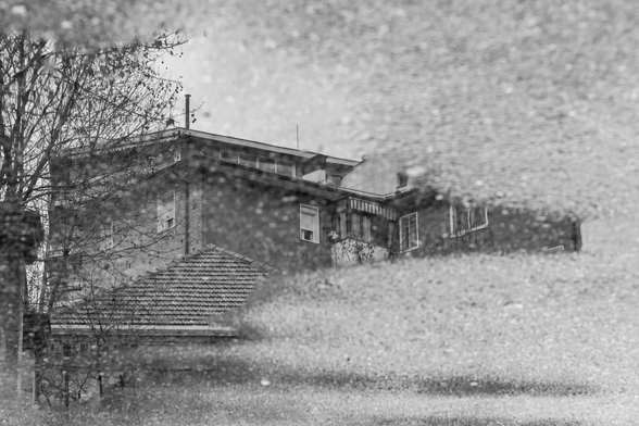 Español: fotografía en blanco y negro del reflejo de un edificio residencial en un charco de agua. 

English: black-and-white photograph of a residential building reflected in a puddle.