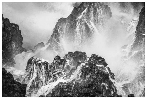 Wellen und Gischt an Lavafelsen.