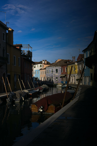 A canal curves past bright coloured houses, the sun catches boats in their raincoats. Nothing much is happening.