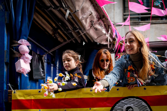 Una nena i dues dones llançant caramels als vianants que havien anat a veure la cavalcada de Sant Medir.