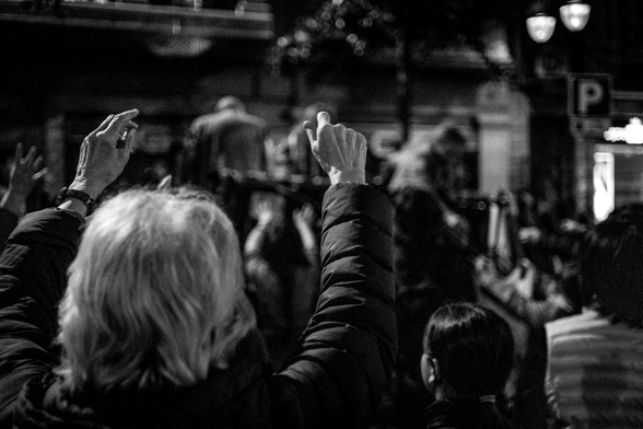 Senyora gran aixeca les mans per intentar agafar els caramels que llencen les colles de Sant Medir al carrer Gran de Gràcia.
