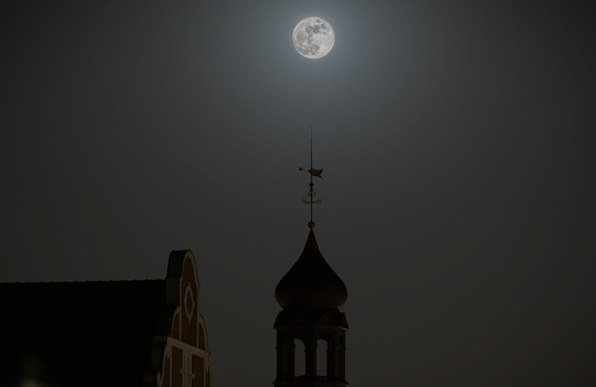 The moon over the top of a spire.