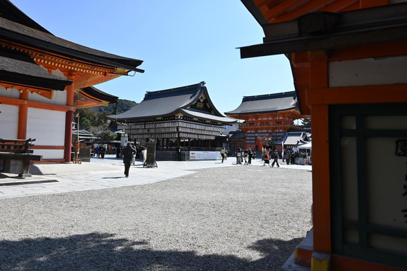八坂神社北門鳥居を入ってちょっと進んだ場所辺りから舞殿。写真左手の建物が本殿で、舞殿の奥に見えるのが南楼門。/ 2026.03.12 八坂神社から