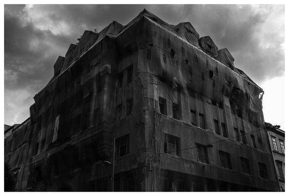 Ein großes Gebäude, vermutlich während der Renovierung/Kernsanierung, ist mit Tüchern verhangen. Der Anblick weckt Assoziationen an eine mit Lappen umwickelte Mumie. 