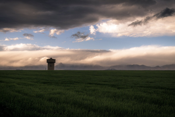 Español: fotografía con un cielo lleno de nubes de tormenta con algunas montañas al fondo y un prado y una torre de agua en primer plano.

English: photograph with a sky full of storm clouds with some mountains in the background and a meadow and a water tower in the foreground.