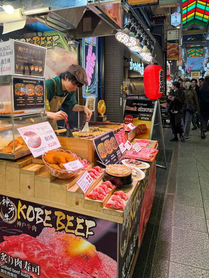 Man grilling meat at a vendor booth in the public market.