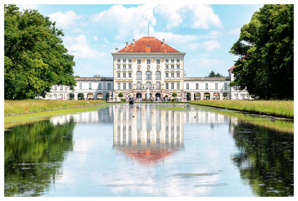 Ein Schlosspark mit Wasserlauf und Schloss.