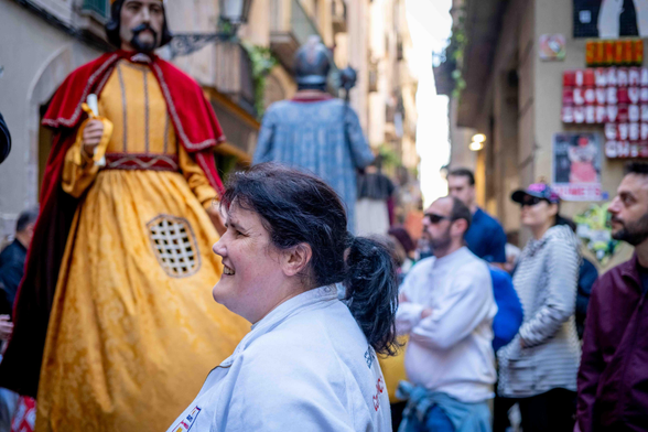 Dona de la colla de gegants, amb els gegants al fons als carrers de Ciutat Vella de Barcelona