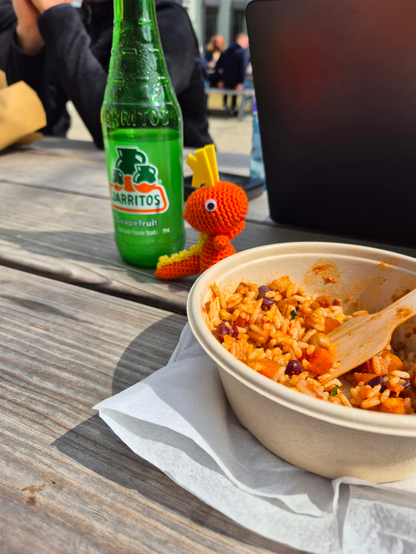 A red crocheted Konqui next to a bowl of Chili