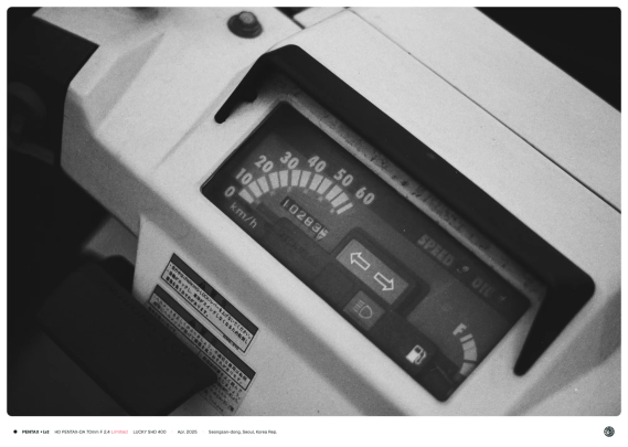 흑백사진. 부채꼴 모양의 속도계가 달린 오토바이의 조작부.