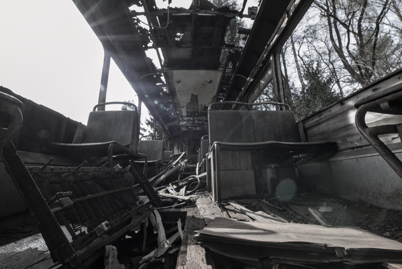 Innenraum eines verlassenen, stark beschädigten Zuges mit zerbrochenen Sitzen und Trümmern auf dem Boden