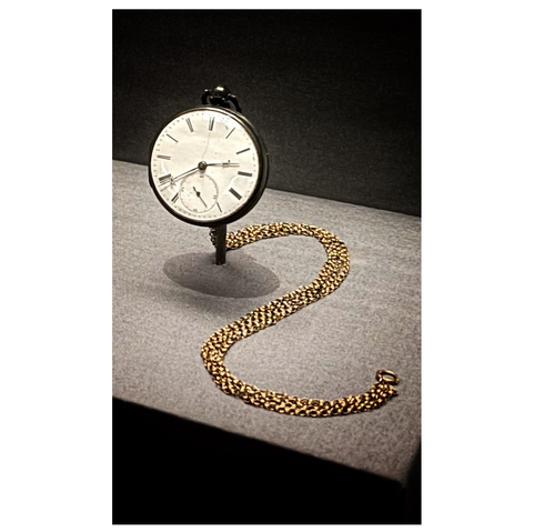 Closeup on a silver pocket watch with a gold chain draped beside it in an “S” shape, in a neutral gray display case.

Displayed in the past exhibition “Superfly: Tailoring Black Style” at the Metropolitan Museum in NYC.

Excerpts from the museum placard:

“Pocket watch and chain owned by Frederick Douglass, 1846
Silver with gold chain”

“In 1894 Frederick Douglass wrote an essay describing the significance of purchasing his first pocket watch, on view here. ‘The possession of a watch in my young days was among the remote possibilities,’ he wrote, as ‘I did not own myself.’ A pocket watch, hung from a heavy chain outside a gentleman's waistcoat, was for Douglass ‘a sign of wealth and respectability,’ and for a formerly enslaved man, the ultimate indication that his time was his own. When he finally acquired one as a free man, he wrote, ‘no article in my ownership has been more serviceable to me,’ as it allowed him to maintain the practice as well as the appearance of sophistication, prosperity, and punctuality.”
