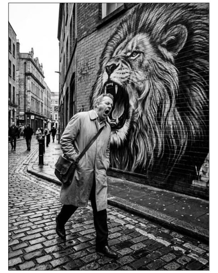 BW pic of a man yawning while walking beside a street artwork representing a lion.