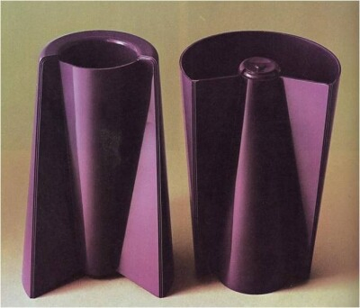 Photo of two identical purple plastic vases, one turned upside down. In both vase orientations there is a receptacle for water and plant stems. Vase designed by Enzo Mari. 