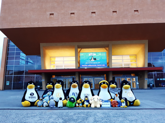 Viele große und kleine Pinguine und andere Plüschfiguren sitzen vor dem Gebäude.