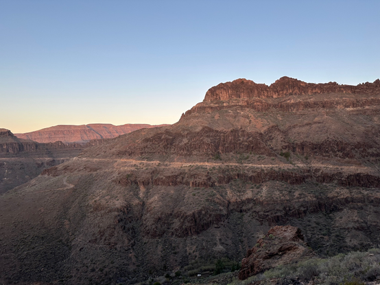 Early morning in the mountains. The walls of the valley lit pink by the sun still hidden behind the ridges.