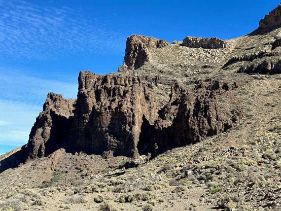 An angular blade-like rock formation in a grey high-altitude mountain landscape.
