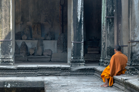 I took this photo at Angkor Wat many, many years ago and it's visible in the low resolution of my camera from the time. it shows a monk in saffron clothes sitting with his back to us on the stone ledge, at an opening of one of the temples between the ancient walls. a bit of sunlight falls into the scene