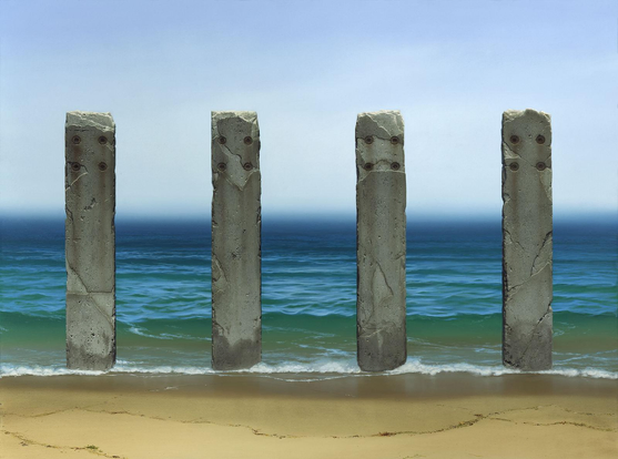 Four weathered pillars of concrete stand at ocean's edge. The sky is a hazy fog that blurs at the horizon above a deep blue sea. Approaching the foreground, sea green water becomes glassy reflecting the sun as the receding tide slowly rolls out depositing a meandering line of detritus on the wet sand.
