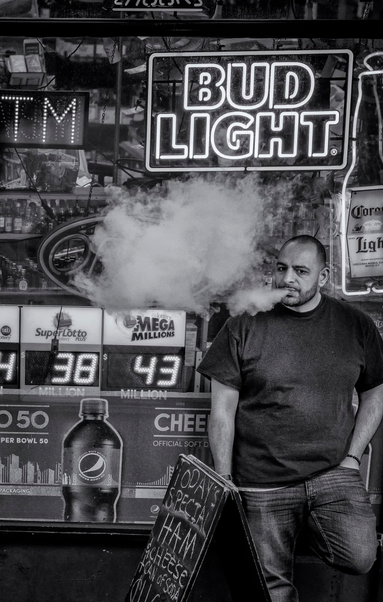 Man exhales a stream of vapor from vape pen in front of convenience store in San Francisco.