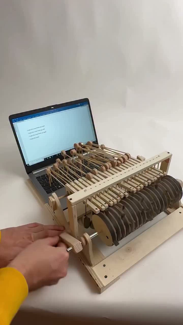 A barrel-organ type contraptions with actuators that type “I hope this email finds you well” on a laptops’s keyboard