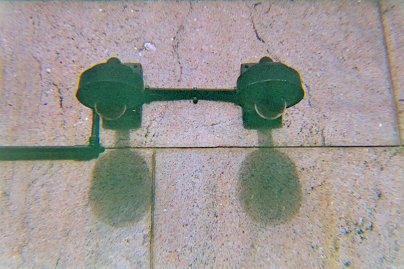 Two black dome-shaped surveillance cameras with shadows right beneath them on a beige granite wall