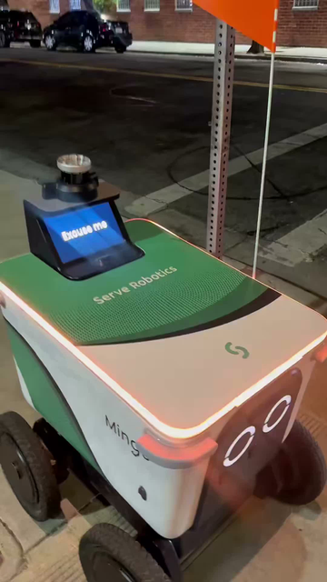 a man yells at a delivery robot because the delivery robot's screen asks the guy to help it by pressing the crosswalk button for it