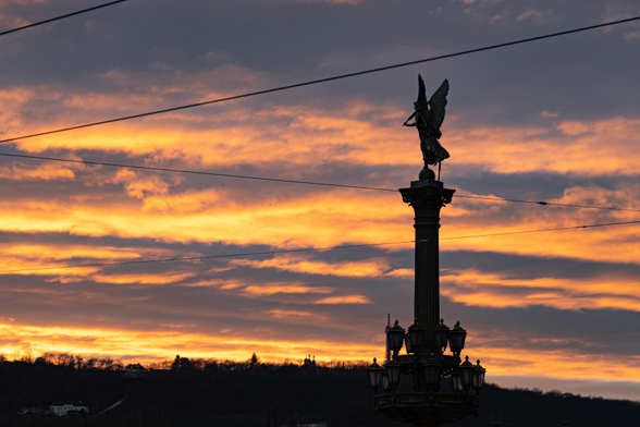 statue silhouette near the Rudolfinum in Prague, taken at sunset against fiery lit up clouds in the sky
