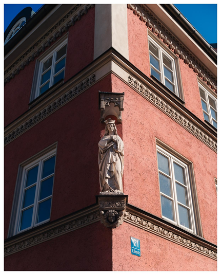 Ecke eines alteren Gebäudes das so von der Sonne beschienen wird, dass rechte hälfte hell, linke dunkel. An der Ecke prankt eine (Marien) Statue.