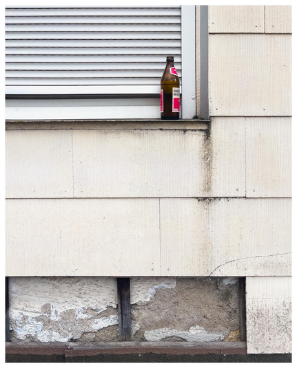 Bier auf Fenstersims an siffiger Hauswand.