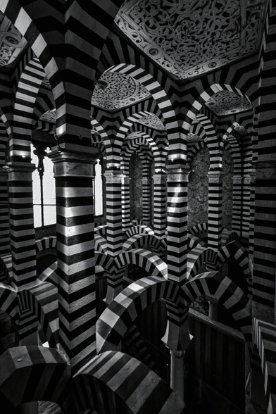 This is a black-and-white photograph inside the Capella of Rochetta Mattei. The Chapel is filled with black an white hoirzontally-striped columns. We are on the second floor of the chapel in this photo. The columns are also arched and make unusual and pretty striking patterns when looked at from a certain angle. It is pretty disorienting.