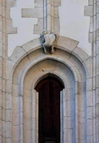 Stone carving of the 'Indecent Man' above a window on the Church of St James in Brno, Czech Republic. The figure, part of the church's Gothic façade, is a small, humorous sculpture of a man exposing himself, added as a playful or symbolic element in medieval architecture.