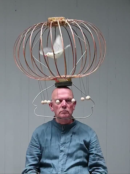 le gourou, en tant que guide spirituel, une cage contenant une colombe de la paix automate fixée sur son auguste tête, invite ses disciples à méditer sur le Mystère de l’Ascension