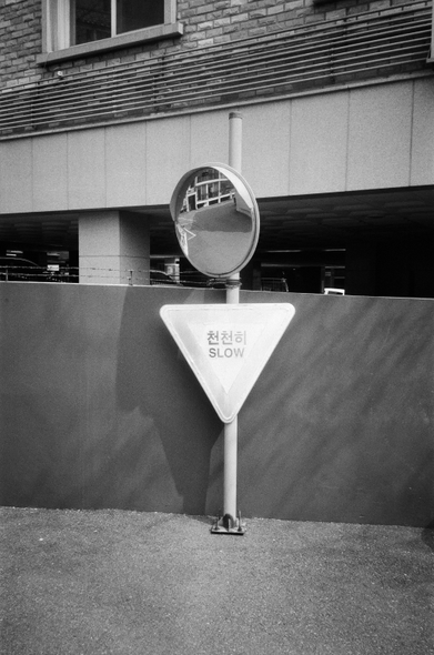 주택가 담벼락 앞에 설치된 '천천히' 표지판과 사각지대용 거울. 기둥보다도 낮게 설치되었다.