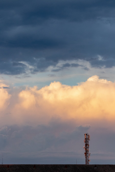 Español: torre de telecomunicaciones ante un cielo tormentoso al atardecer, con nubes en tonos dorados y azul oscuro.

English: telecommunications tower against a dramatic sunset sky, with clouds in golden and dark blue tones.