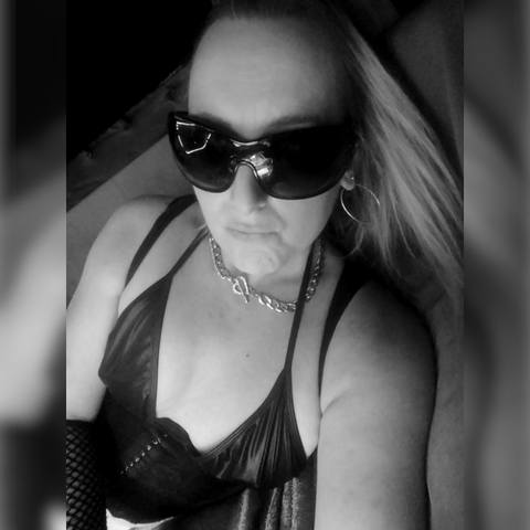 a black and white photo of me where i look inexplicably glamorous. (a white woman with blonde hair and a black PVC bikini lies on one side. her hair happens to fall in a way that makes it look impossibly good.